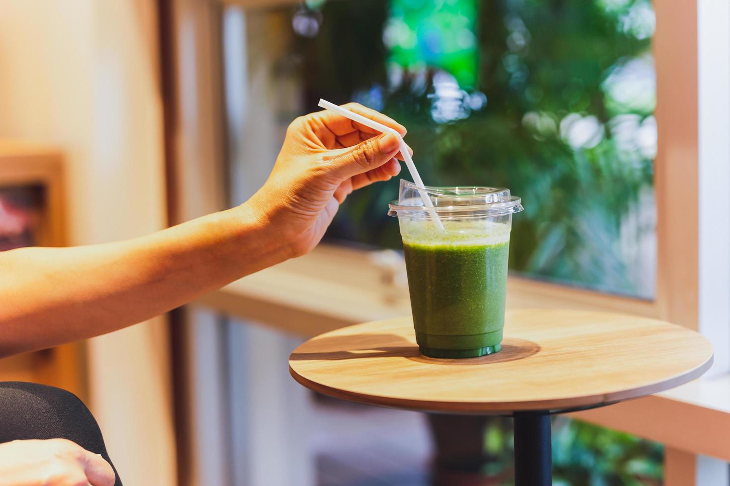 concepto de dieta saludable mujer bebiendo batido verde en la cafetería. foto