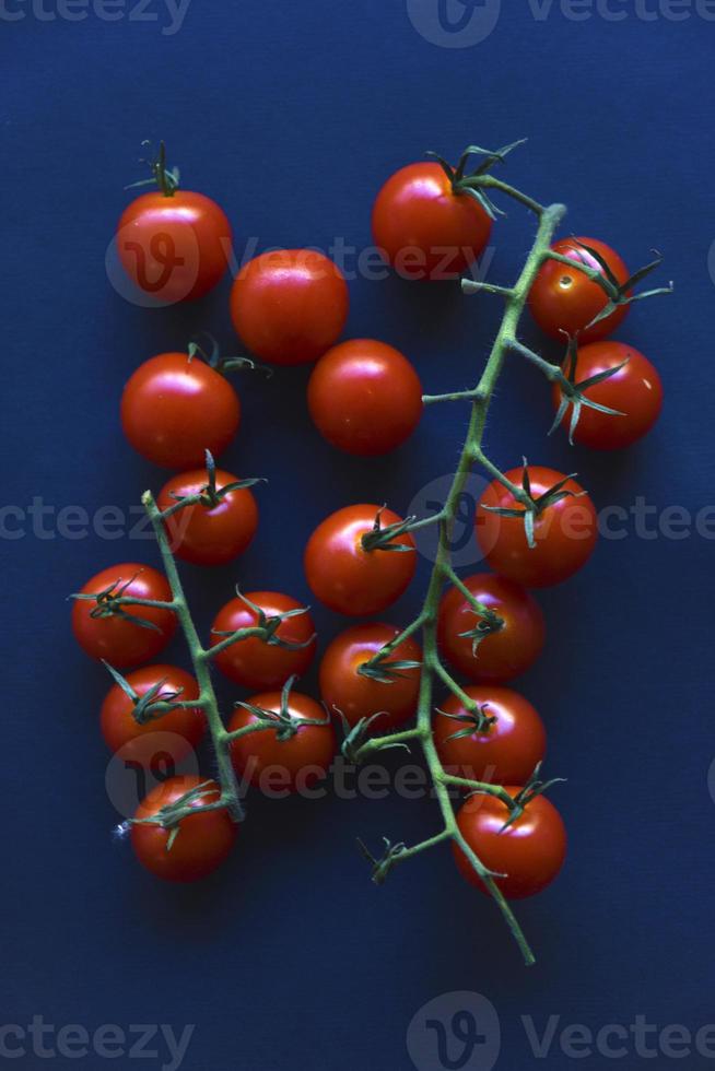 Small cherry tomatoes are yellow and red in a paper container. Small tomatoes on a black background. photo