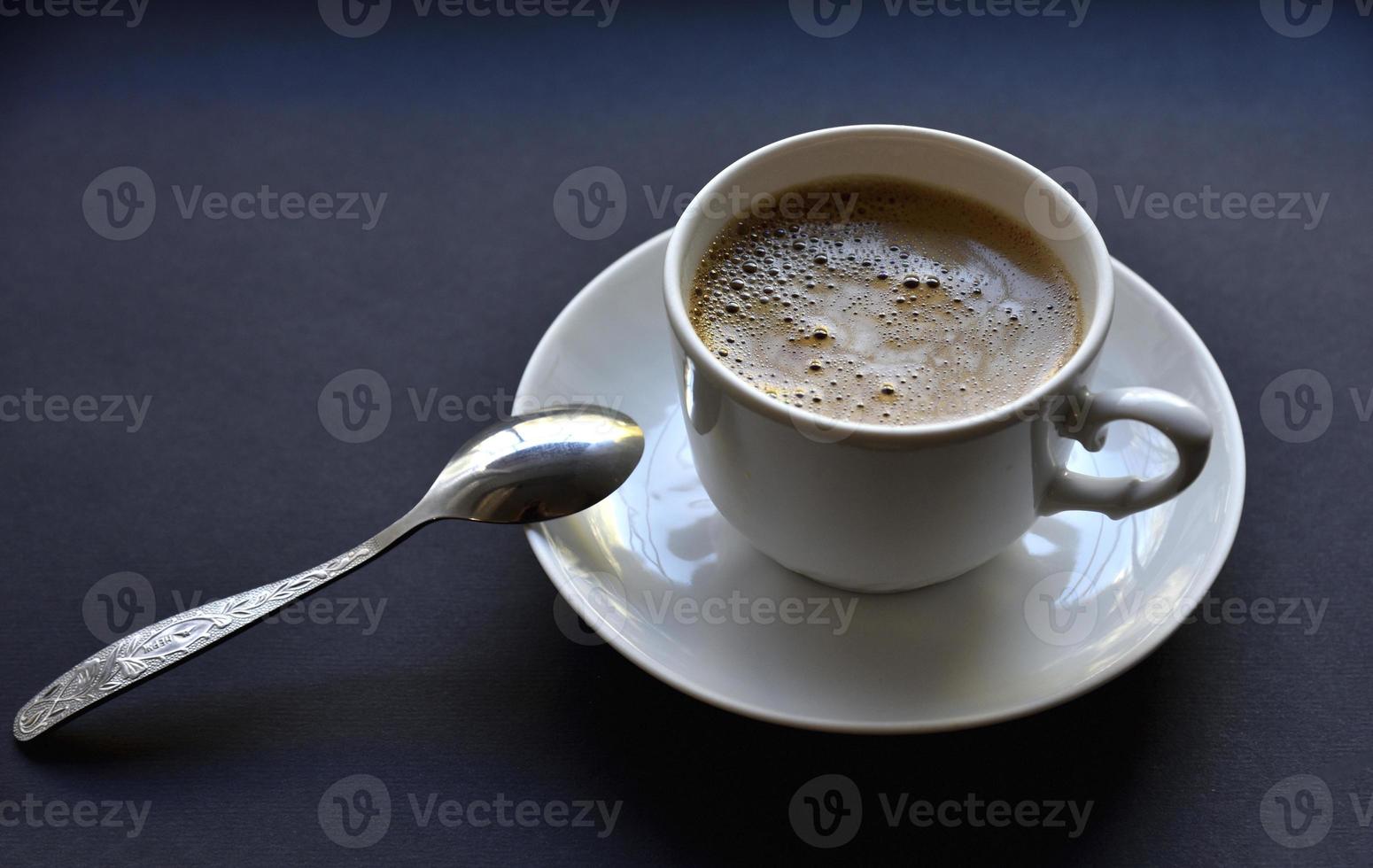 Juicy freshly brewed coffee with foam in a white cup on a black background. Beautiful cup of coffee close-up from above. photo