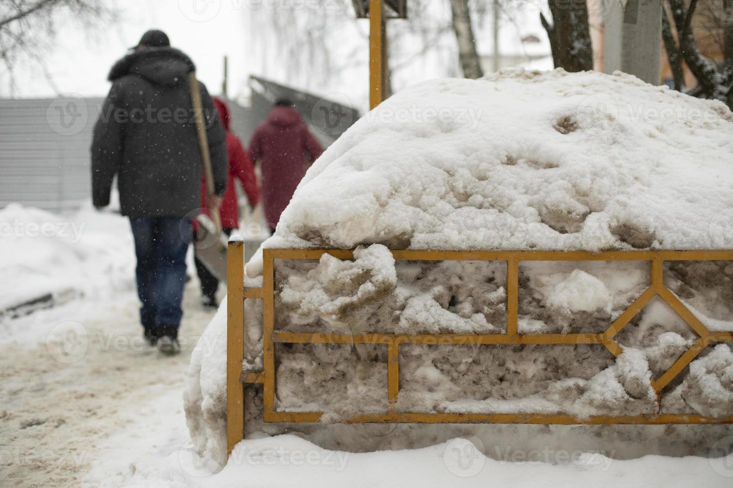 Snow in yard. People go to clean up snow. Snow behind fence. photo
