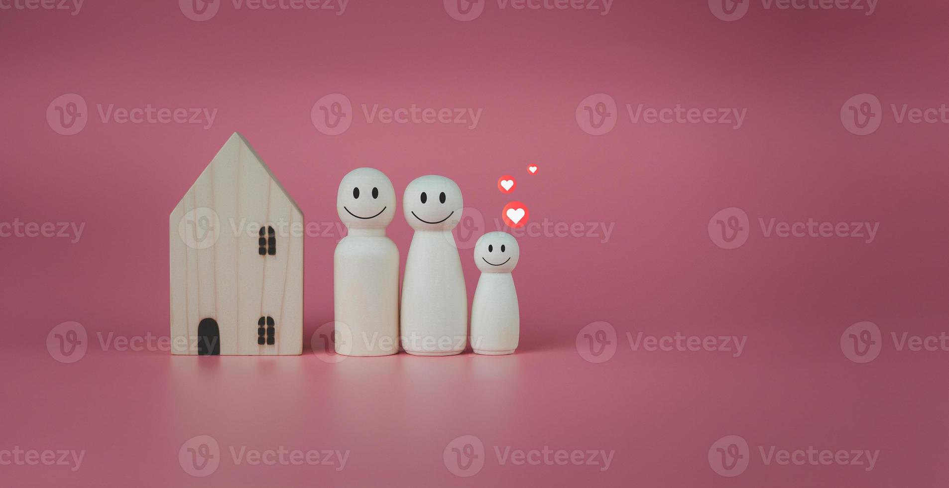 Happy house concept. Model house with wooden dolls standing lined up on pink background and heart icons. Indicates happiness and love in the home. photo
