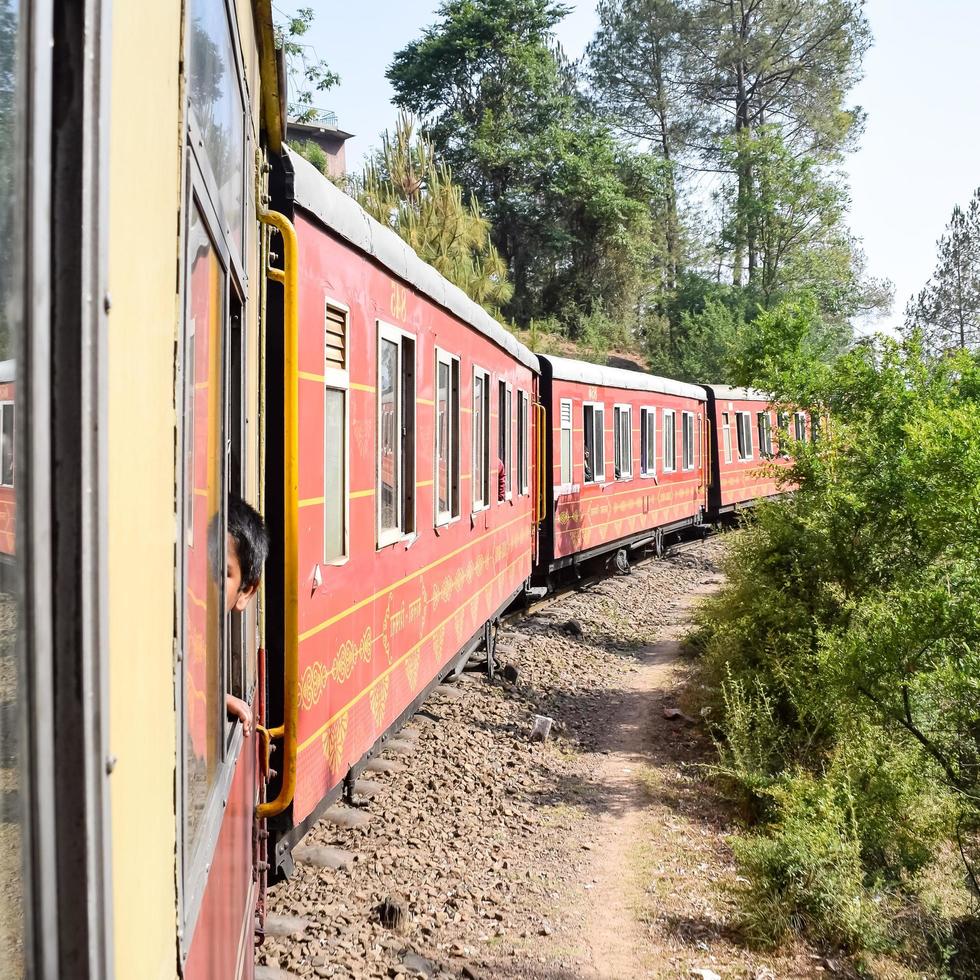 Shimla, Himachal Pradesh, India - May 14, 2022 - Toy train Kalka-Shimla route, moving on railway to the hill, Toy train from Kalka to Shimla in India among green natural forest photo