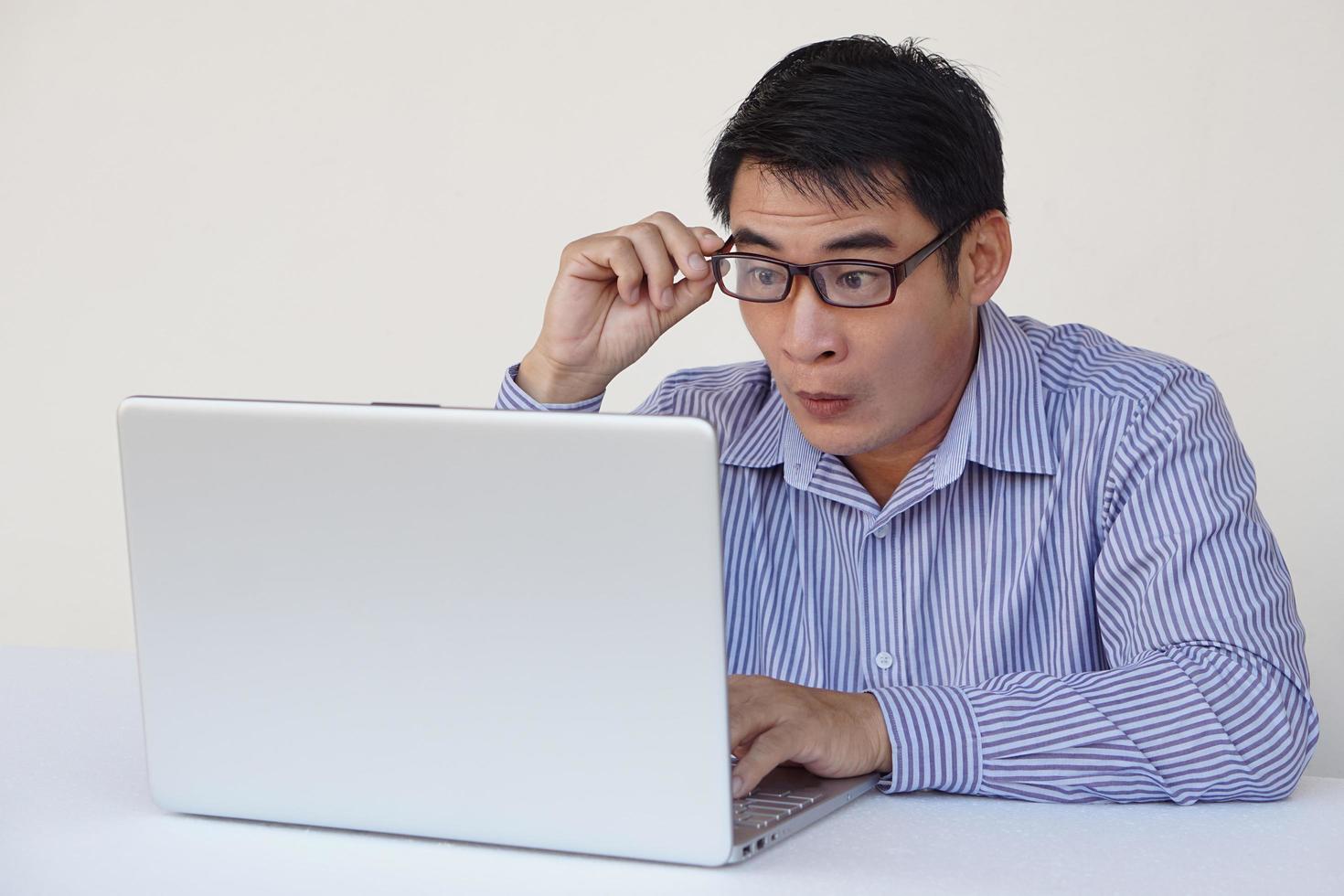 Asian man feels surprised and excited during surfing internet on laptop computer. Concept, Emotional expression. Omg.Wow. feeling. Online working, working with data. photo