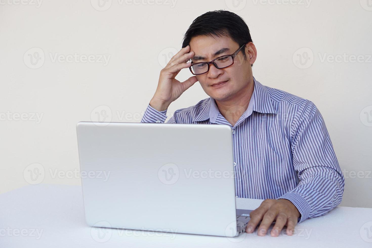 Asian middle-aged man office worker feels heachache, looks serious, think and plan something during working on laptop computer. Concept , Health problems , work with data. photo