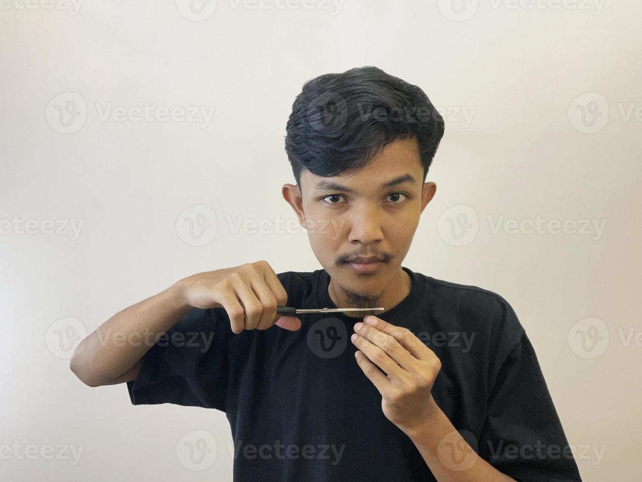 man cutting his own beard using scissors by himself photo