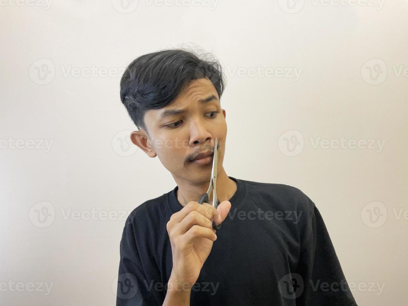 man cutting his own beard using scissors by himself photo
