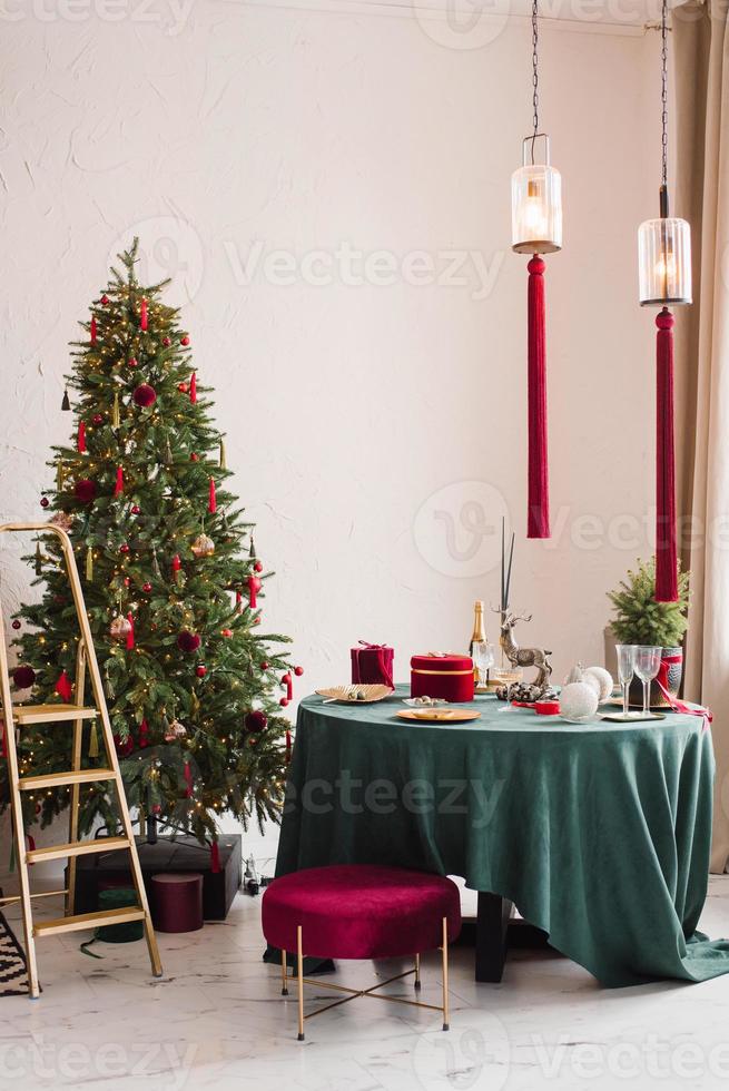Stylish luxurious interior of the dining room with a Christmas tree. A chair near the round table and a stepladder. Classic modern house photo
