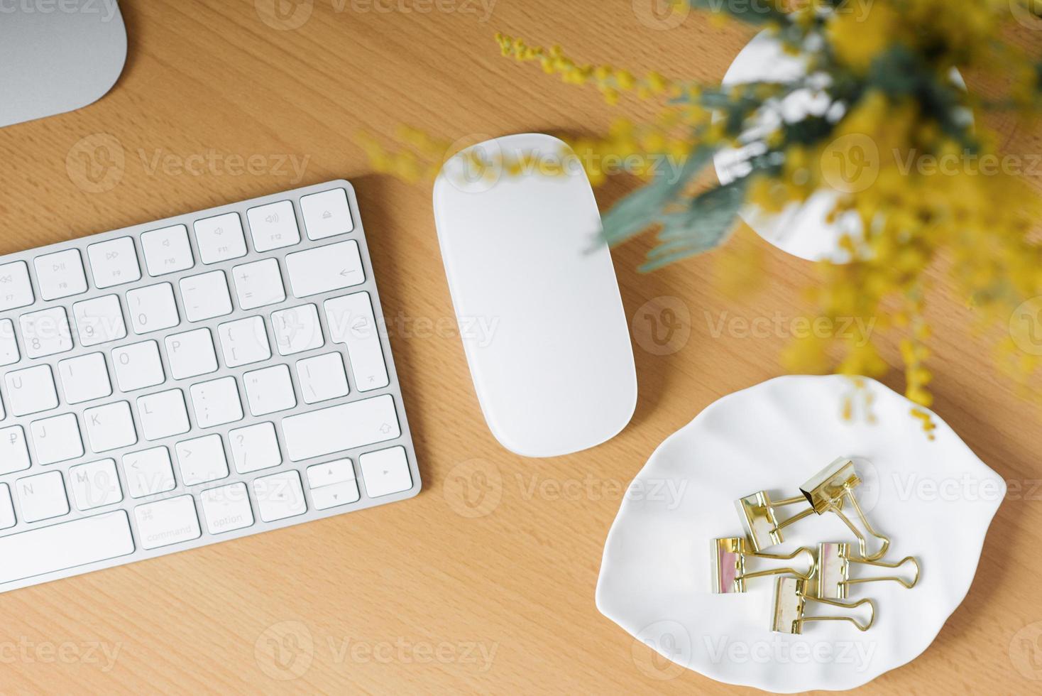 Home office with a computer, a bouquet of mimosa flowers in a vase. photo