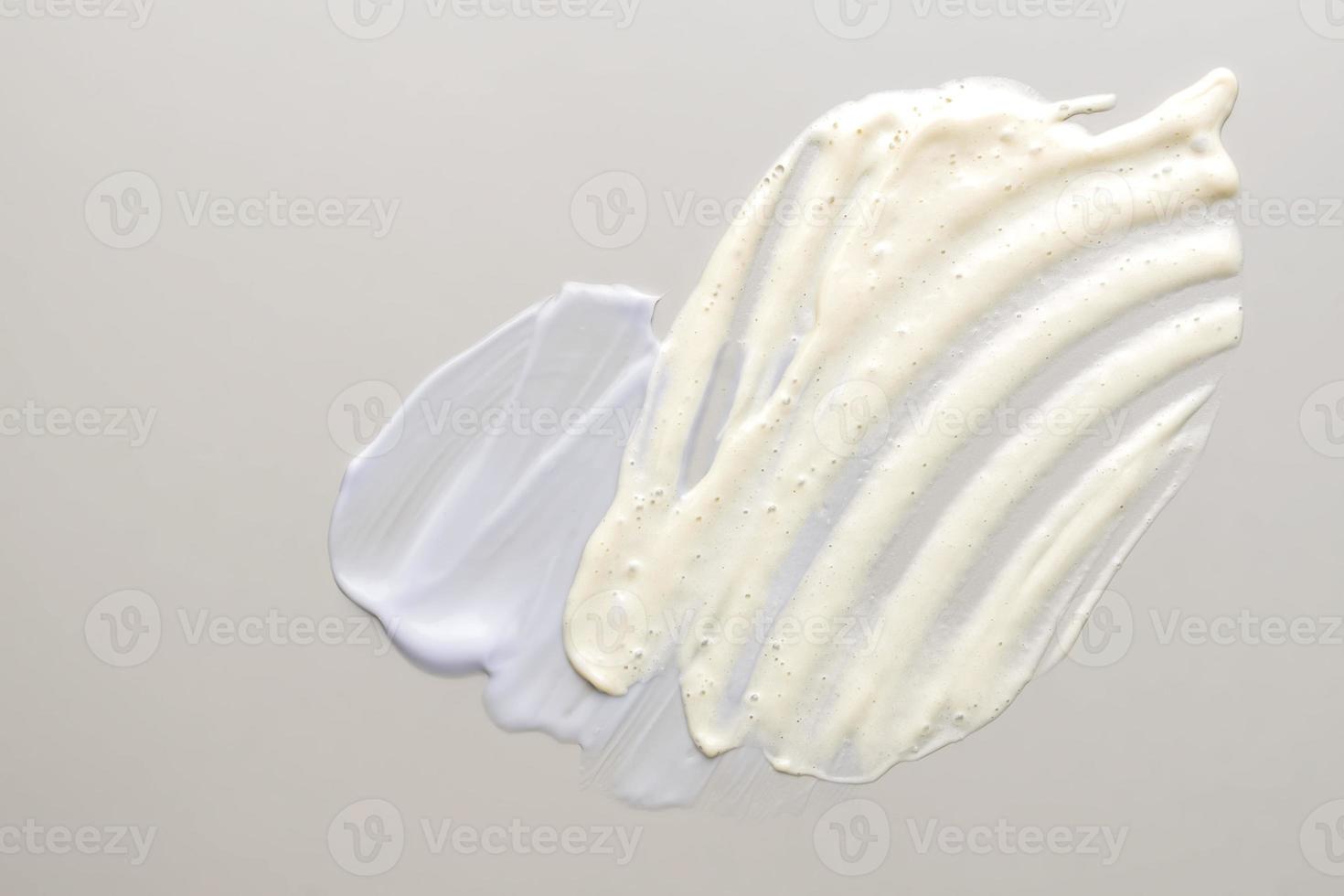 crema blanca y crema cosmética loción humectante trazos en beige pastel. higiene, producto para el cuidado de la piel textura cremosa. crema facial de belleza y muestra de manchas de frotis de limpieza sobre fondo de color foto