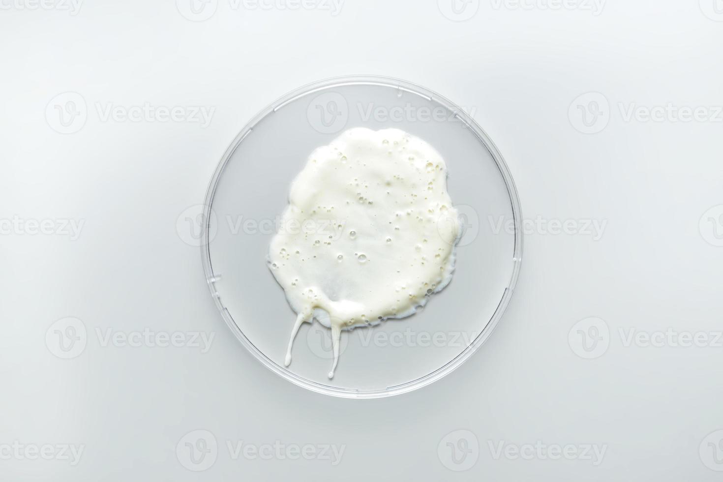 White cosmetic face cleansing foam texture in petri dish. Lotion smear on gray background. Beauty skincare product swatch. cream smudge photo