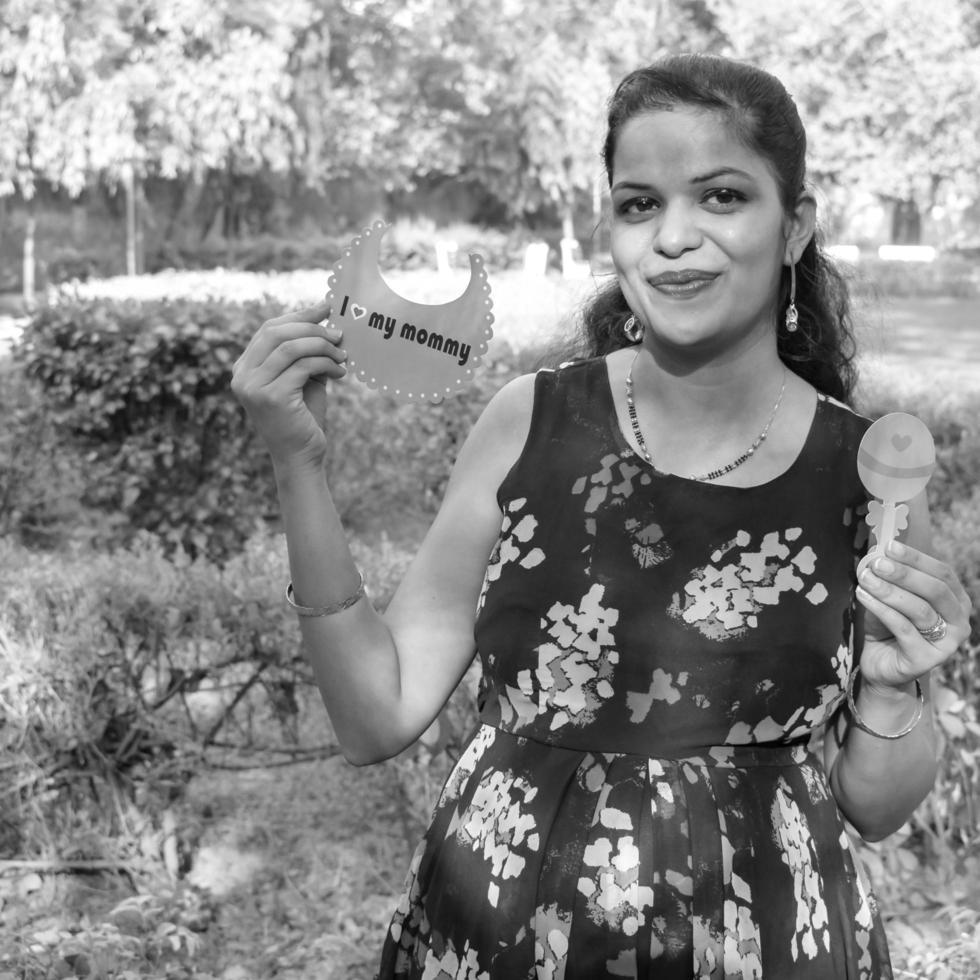 Indian couple posing for maternity baby shoot. The couple is posing in a lawn with green grass and the woman is falunting her baby bump in Lodhi Garden in New Delhi, India - Black and White photo