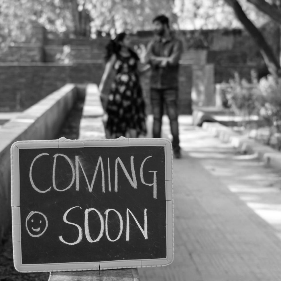 pareja india posando para una sesión de fotos de maternidad. la pareja está posando en un césped con hierba verde y la mujer está faluntando su panza en el jardín de lodhi en nueva delhi, india - blanco y negro