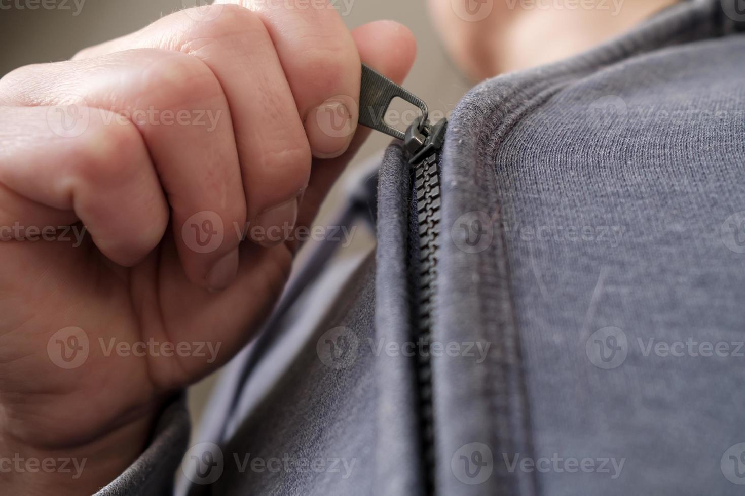 Female hand buttoned the zipper on an old, worn hoody. Bottom view. photo