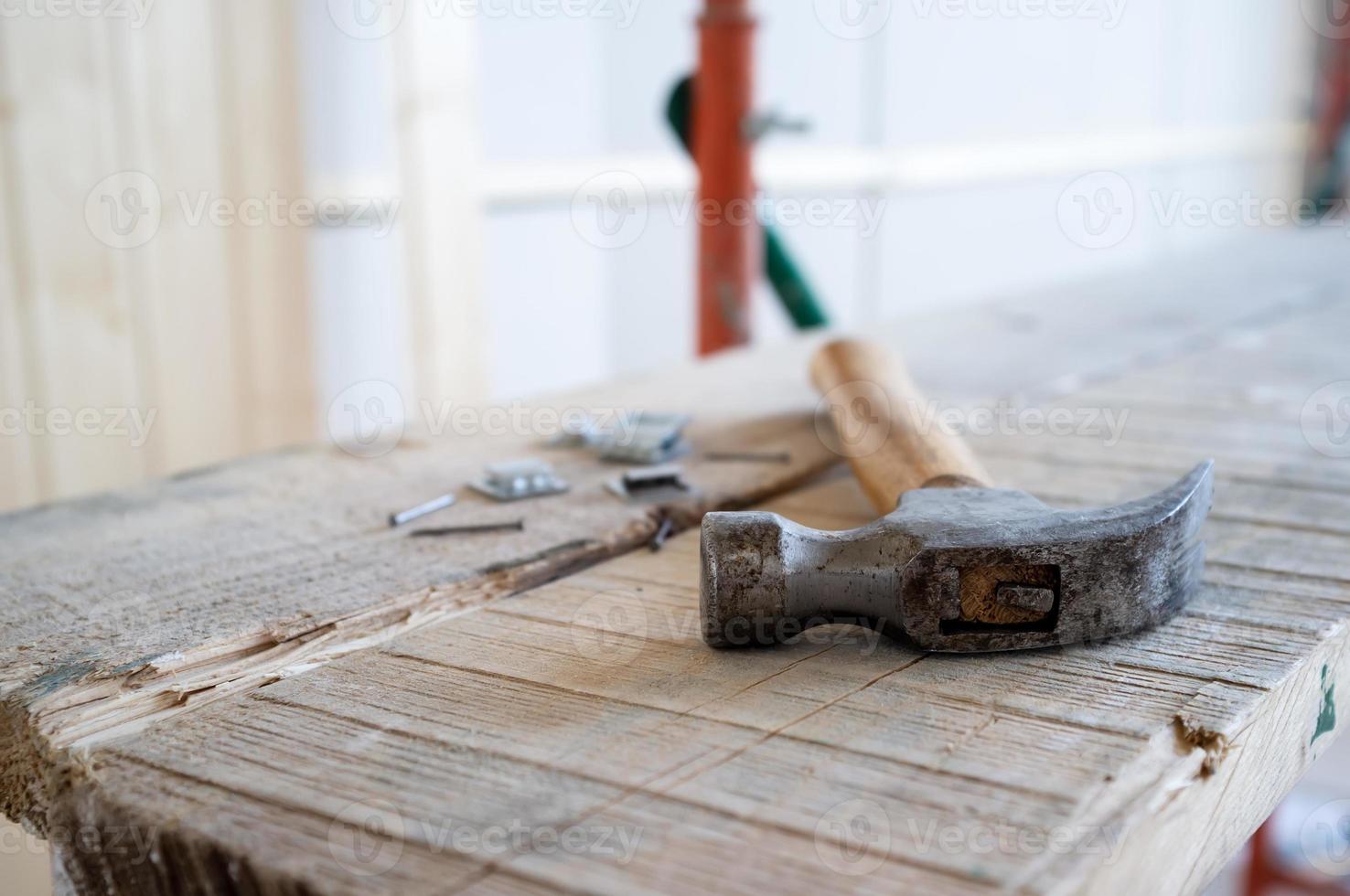 Hammer and nails lie on the scaffolding, against the background of a wall made of wooden slats. Work process. Home renovation. photo