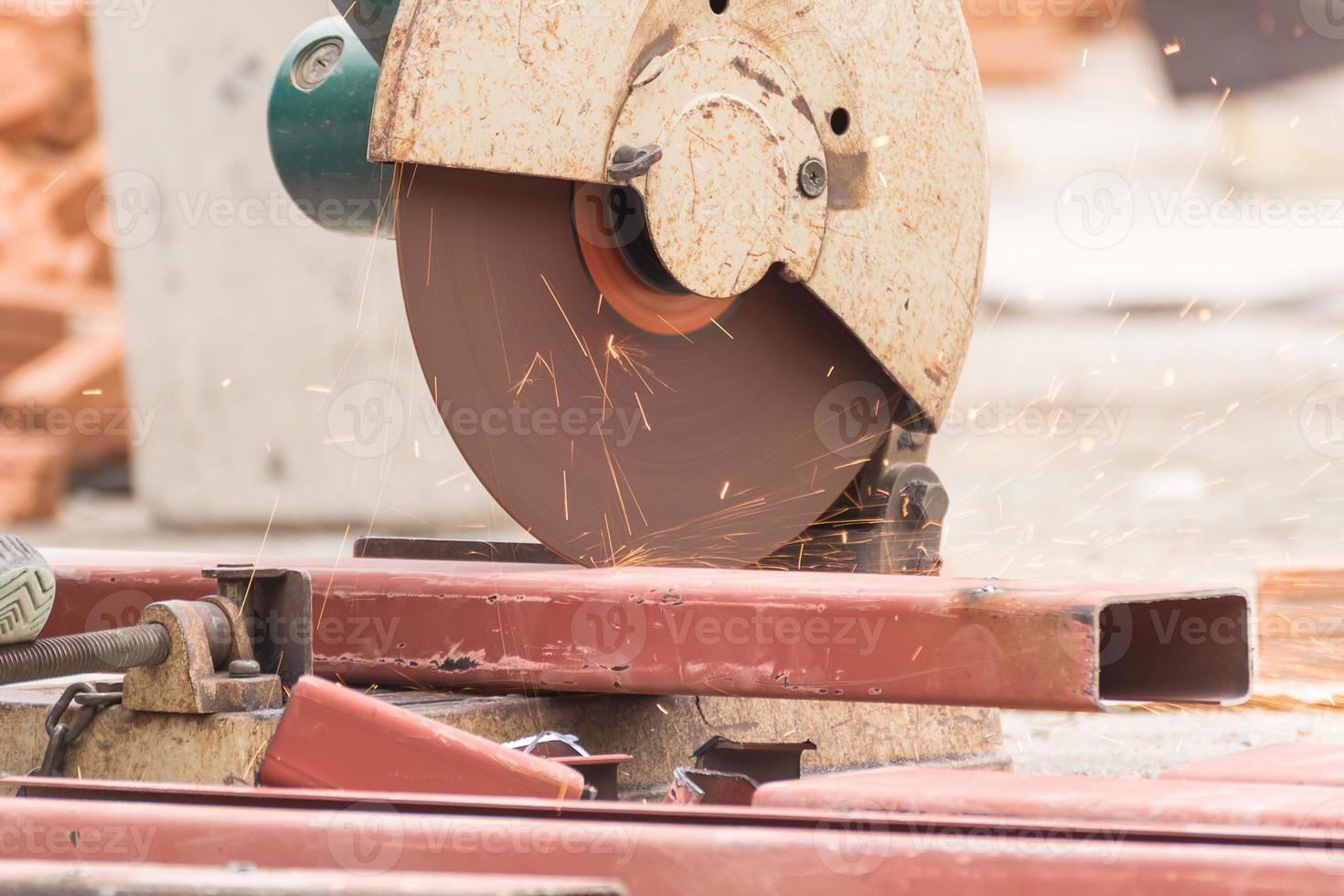 Worker cutting metal with grinder in construction site photo