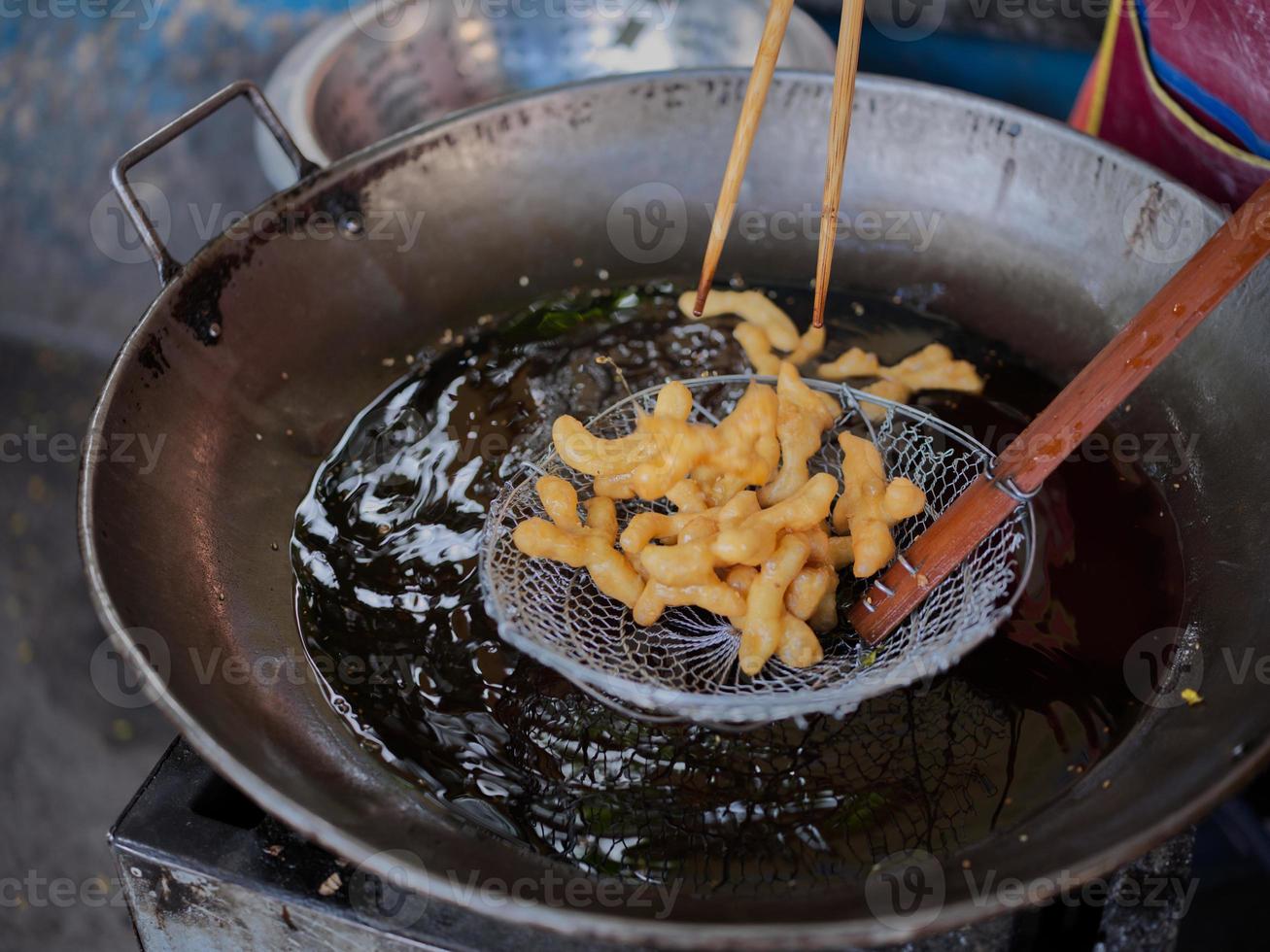 Die cut of Deep fried Chinese Doughnut in an big oil pan photo