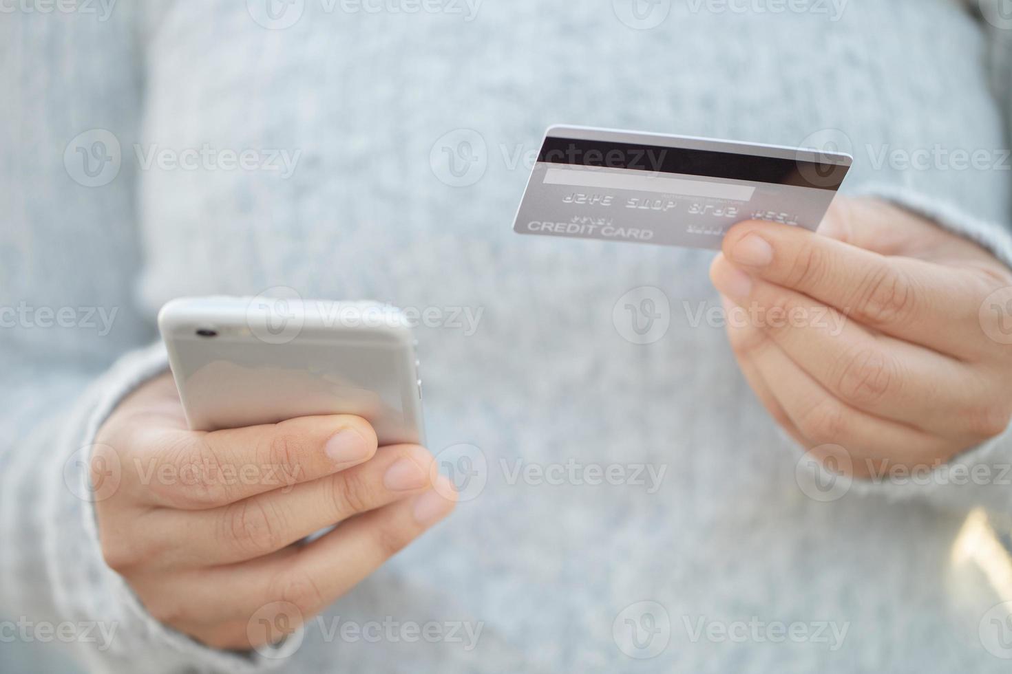 una mujer que usa una tarjeta de crédito para pagar productos en línea con un teléfono móvil foto