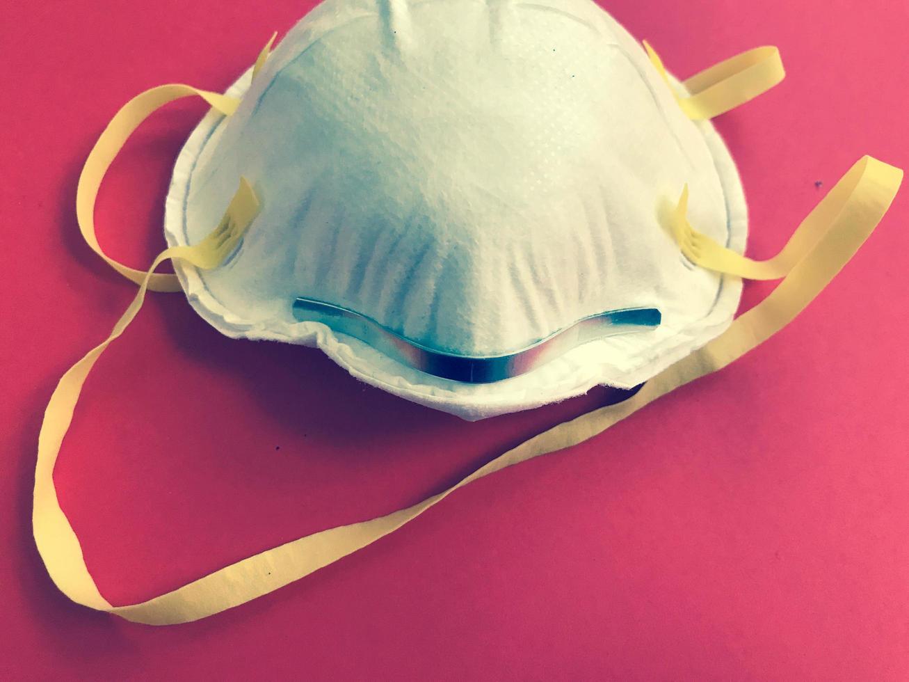 Disposable white protective medical mask for protection against dangerous deadly diseases of microbes and viruses with coronavirus covid-19 on a red background photo