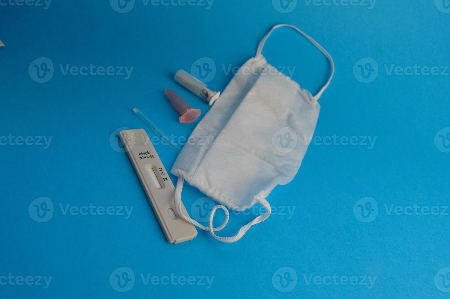 antibody test. a strip for self-diagnosis for coronavirus infection on a blue background. next to the test, a disposable mask, a lancet and a pipette for taking an analysis with a container for blood photo