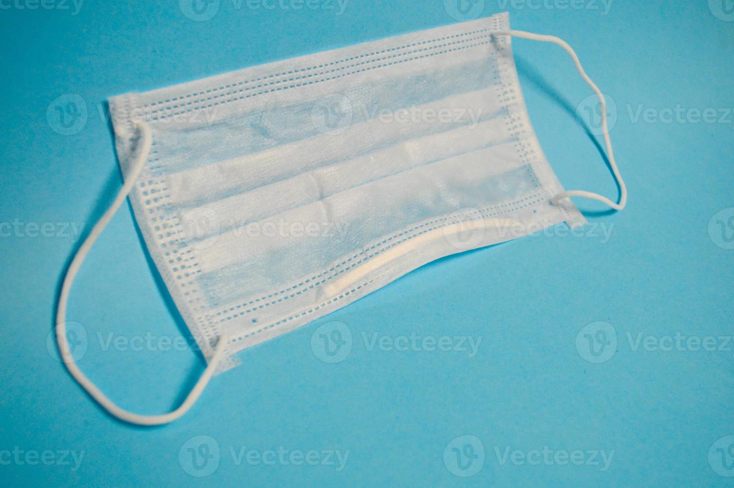 White protective medical mask disposable for protection against dangerous deadly diseases of microbes and viruses with coronavirus covid-19 on a blue background photo