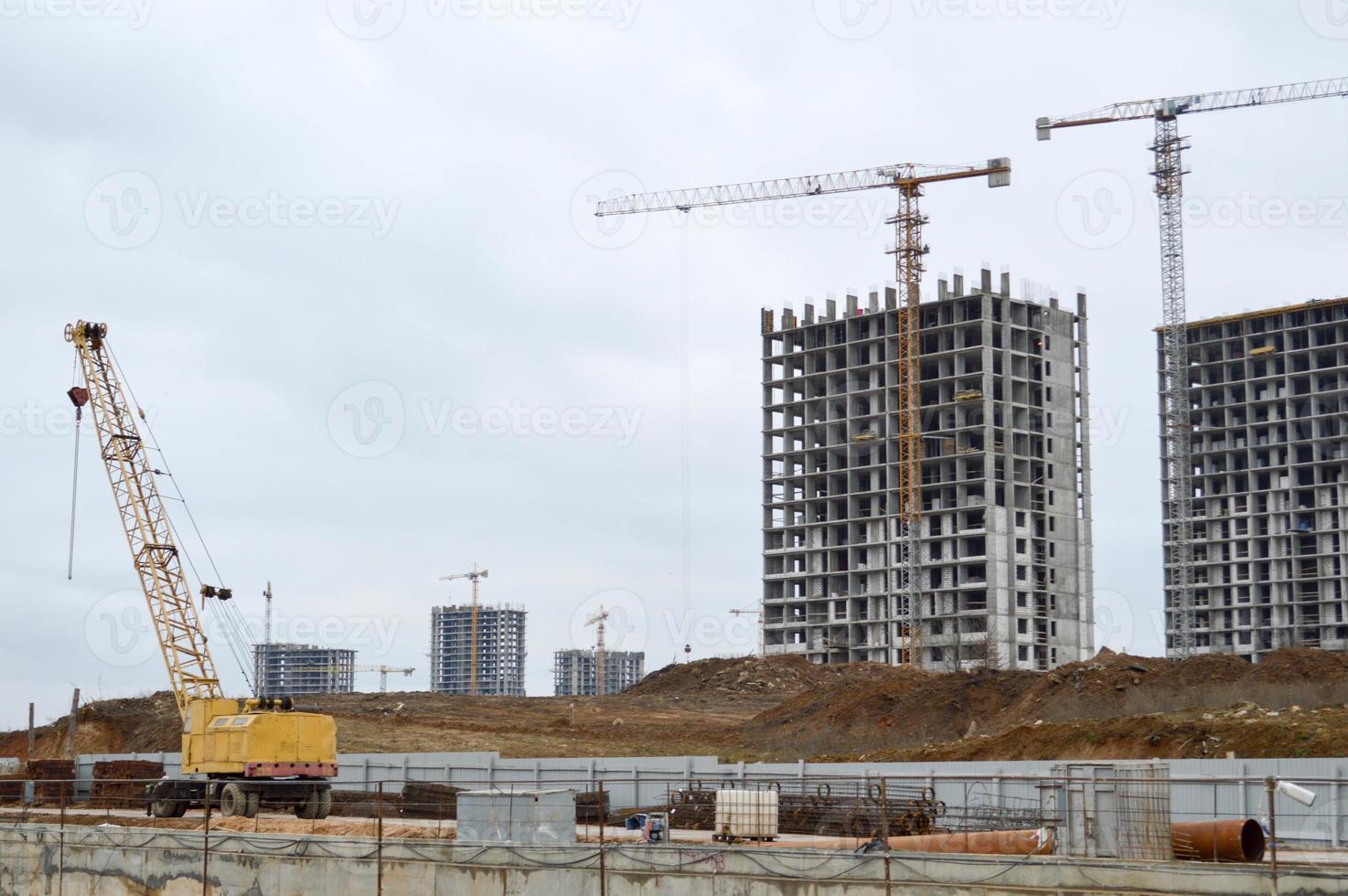 Construction of large modern monolithic frame houses, buildings using industrial construction equipment and large high cranes. Construction of the building in the new micro district of the city photo