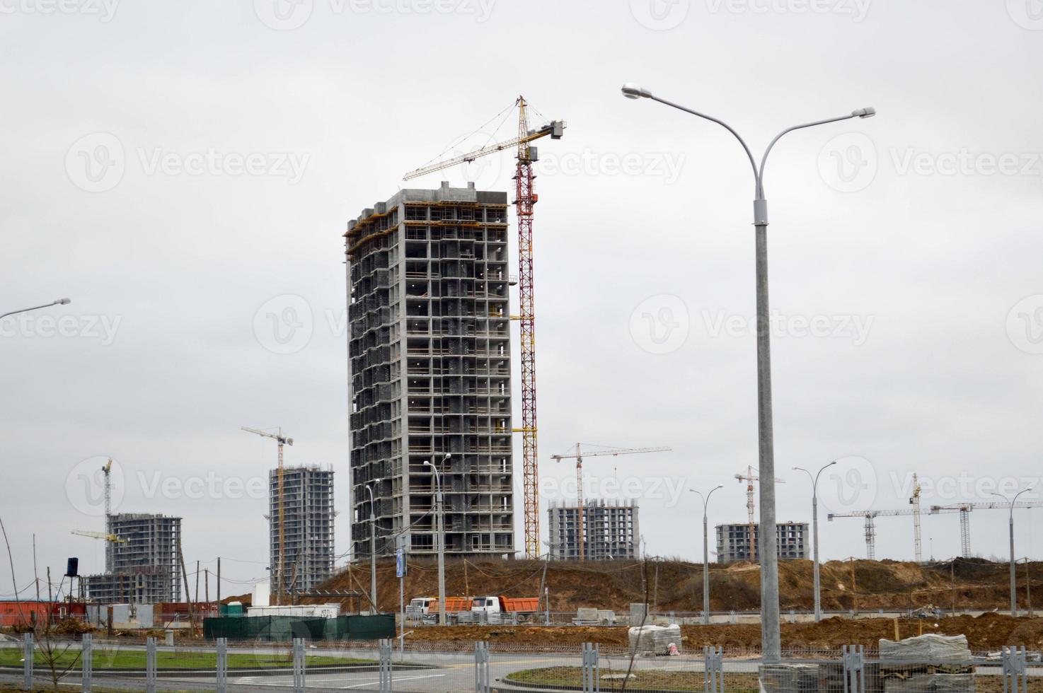 Construction of large modern monolithic frame houses, buildings using industrial construction equipment and large high cranes. Construction of the building in the new micro district of the city photo