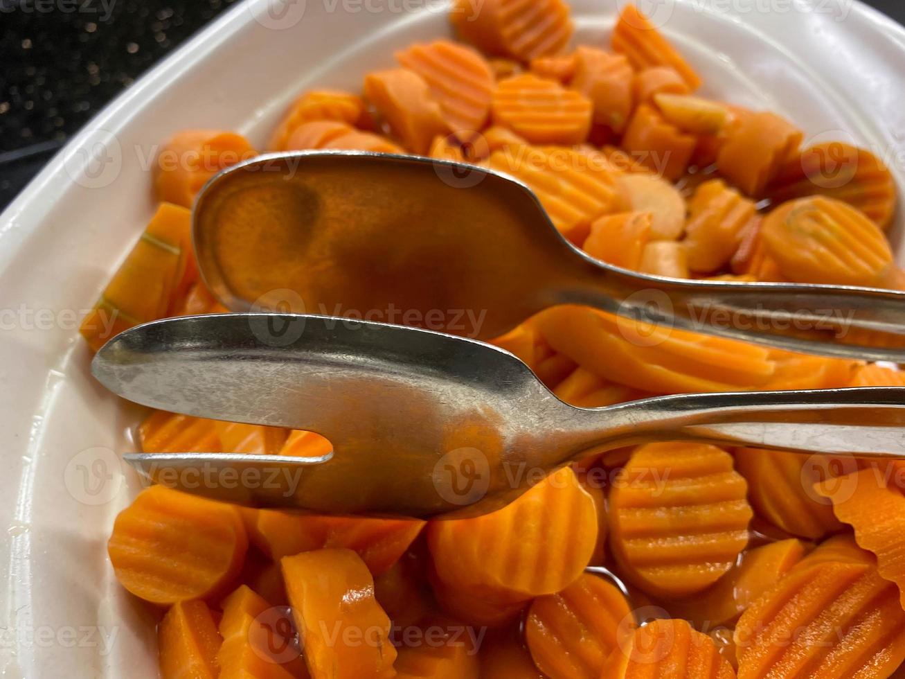 Delicious orange fresh carrots cut into thin circles healthy vegetable salad cutting in a plate with tongs photo