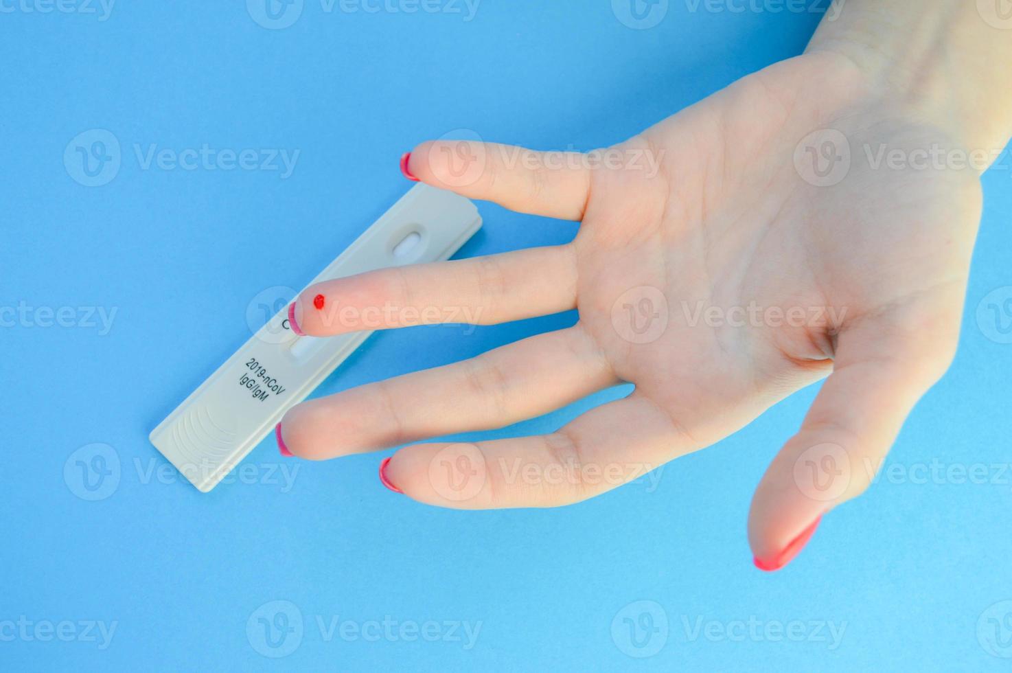 blood test for the diagnosis of coronavirus. a girl with a bright red manicure has a drop of blood on her ring finger. lancet finger puncture, home rapid test photo