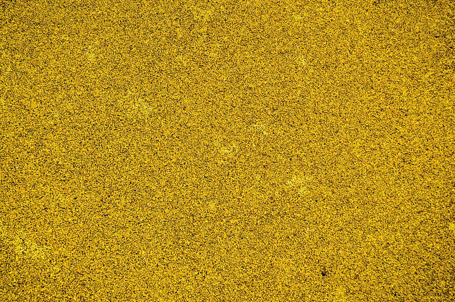 Yellow bright soft rubber flooring safe for sports and workout or on the playground from the many small round pebbles pressed. Background, texture photo
