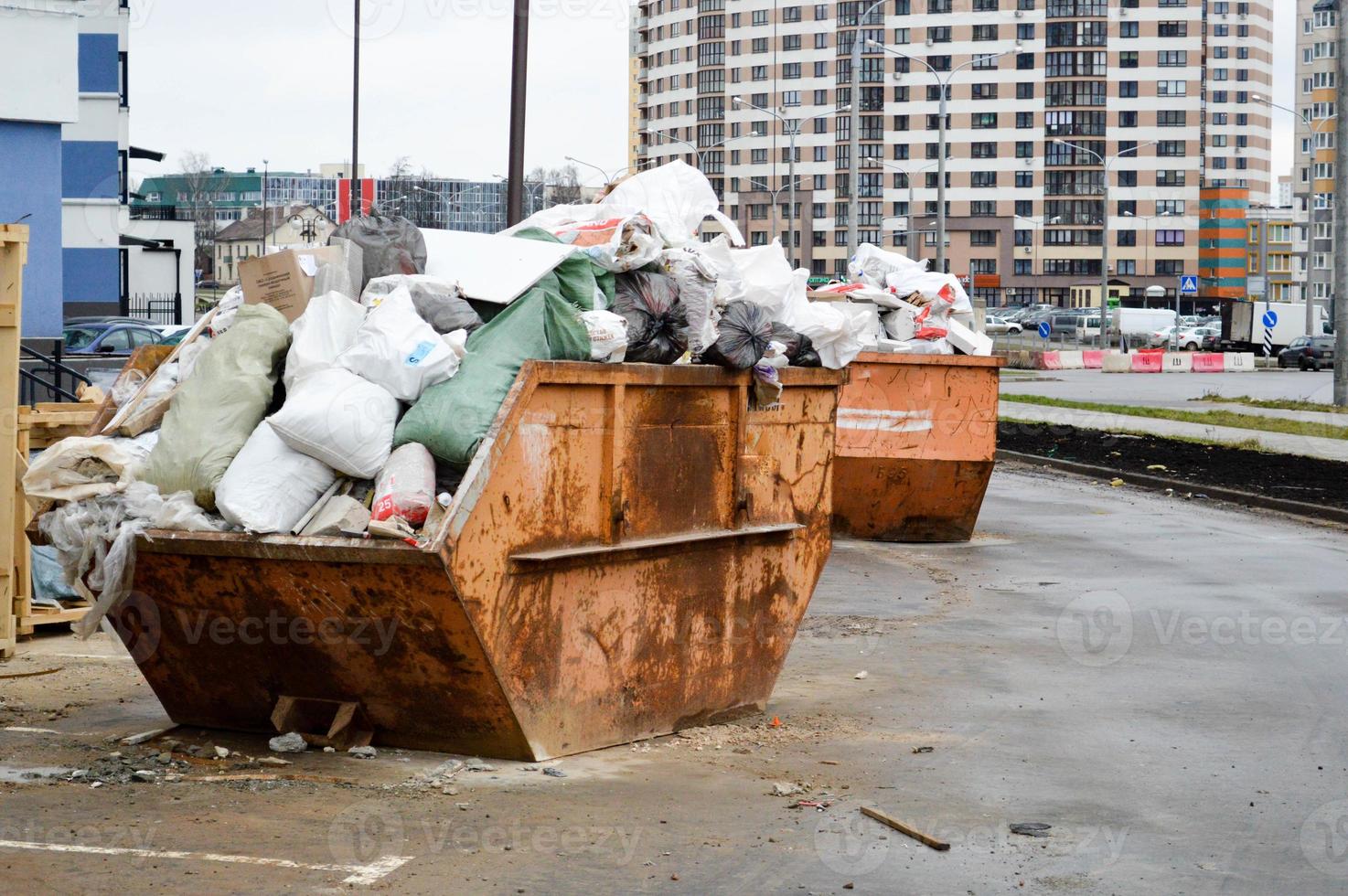 gran cubo de basura industrial de hierro. un lío de basura con suciedad, mala seguridad, condiciones insalubres y contaminación ambiental en un sitio de construcción industrial foto