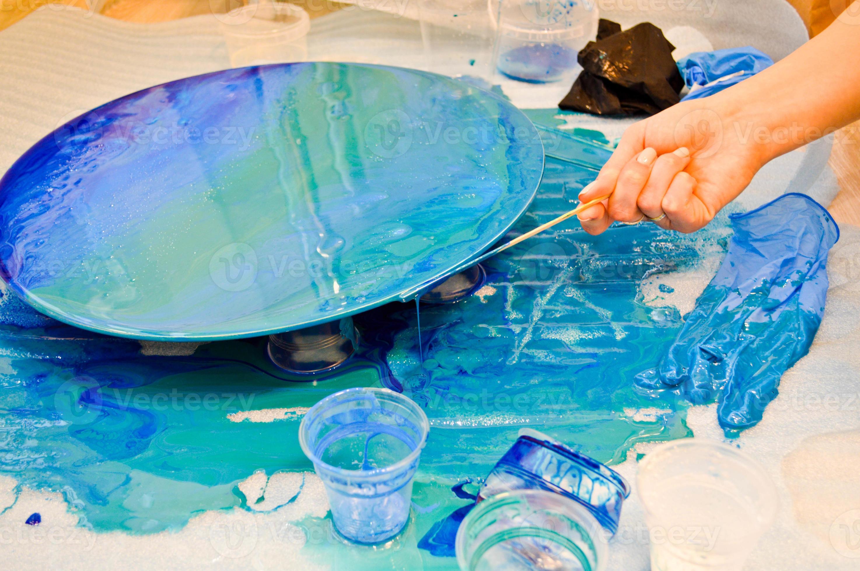 The process of creating a home-made trendy abstract modern pattern painted  with a brush of acrylic blue multi-colored resin on a round wooden board  14026194 Stock Photo at Vecteezy