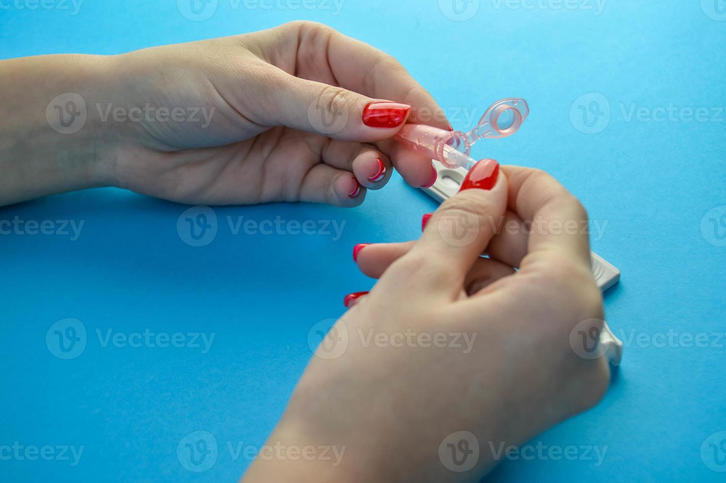 medical diagnostics. girl with red manicure holds a lancet for a finger piercing. capillary blood, diagnostics of their health to identify an infectious disease photo