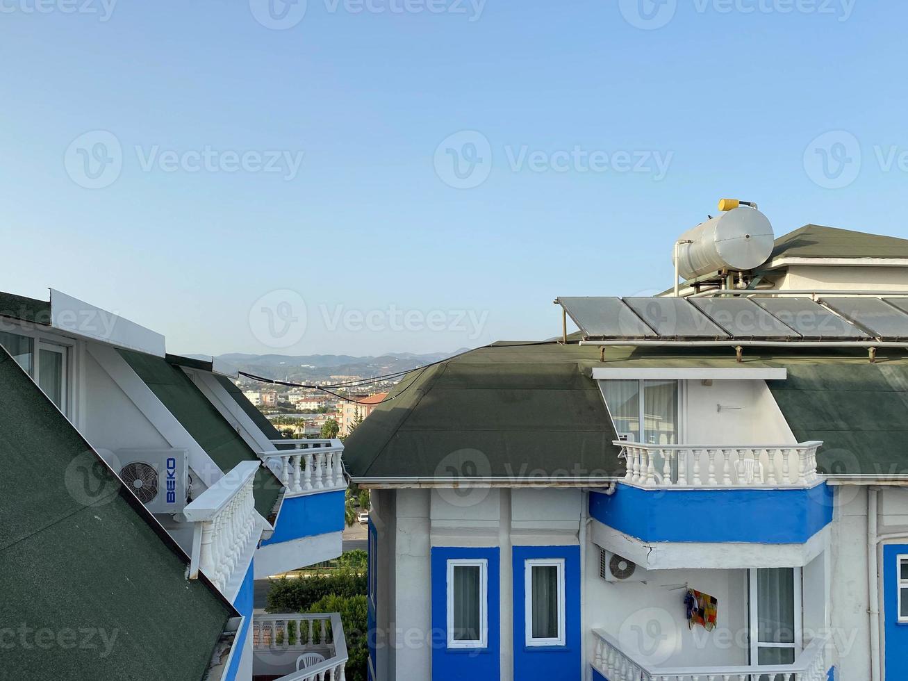 View of the roof of a building in a warm tropical country with solar panels and a water tank on the roof. Energy efficient eco-friendly technologies photo