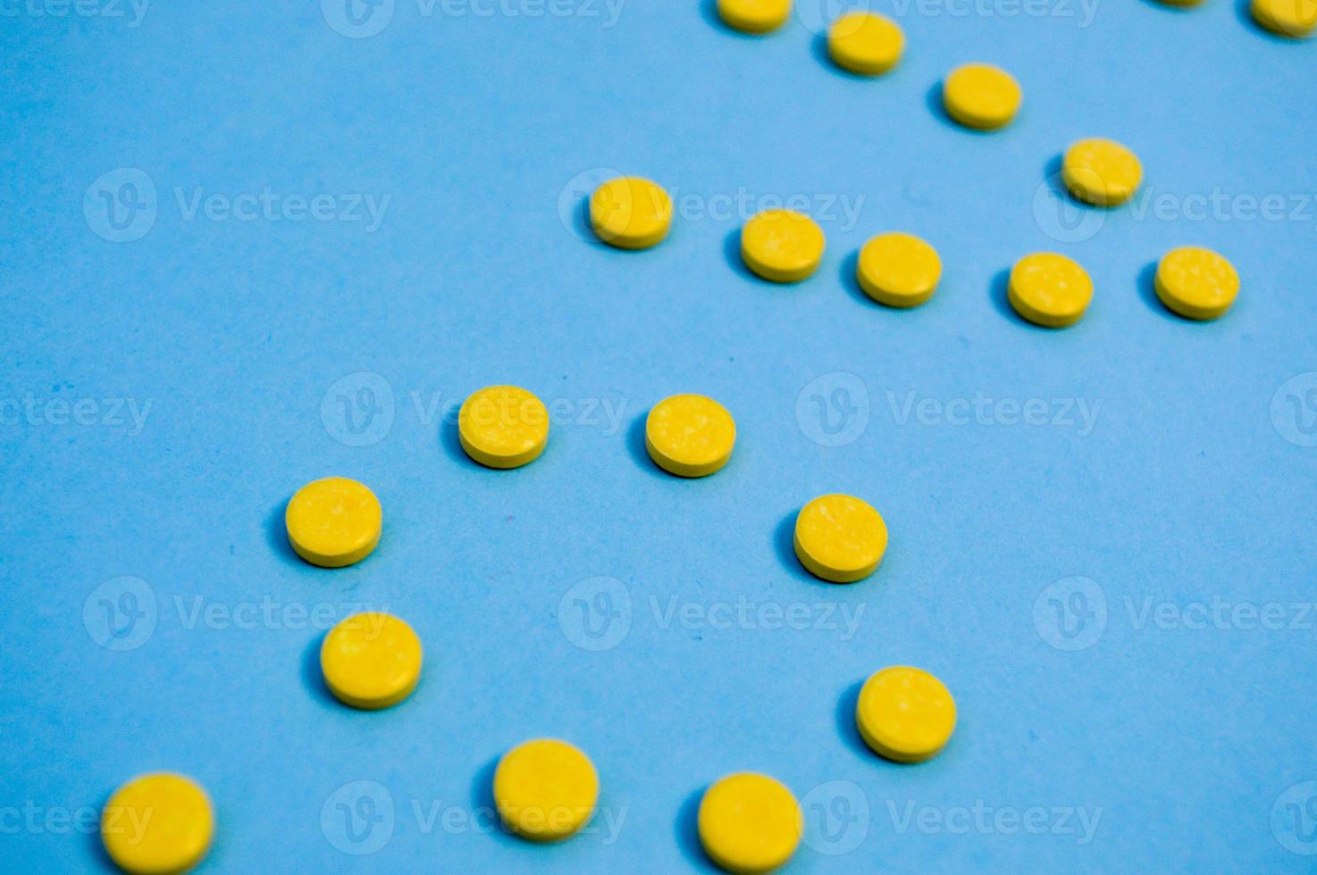 Yellow round medical pharmaceutical for the treatment of diseases and the killing of microbes and viruses pills and vitamins medicines for coronavirus on a blue background photo
