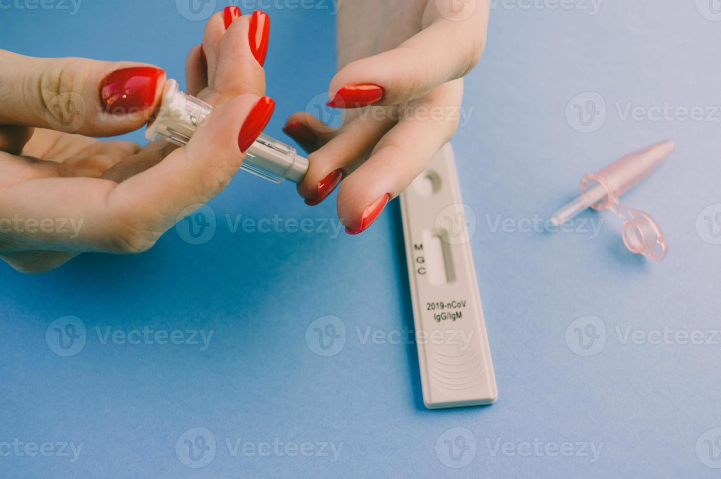 finger puncture to diagnose coronavirus. girl with red manicure makes herself an analysis on her own. a quick blood test to diagnose coronavirus photo