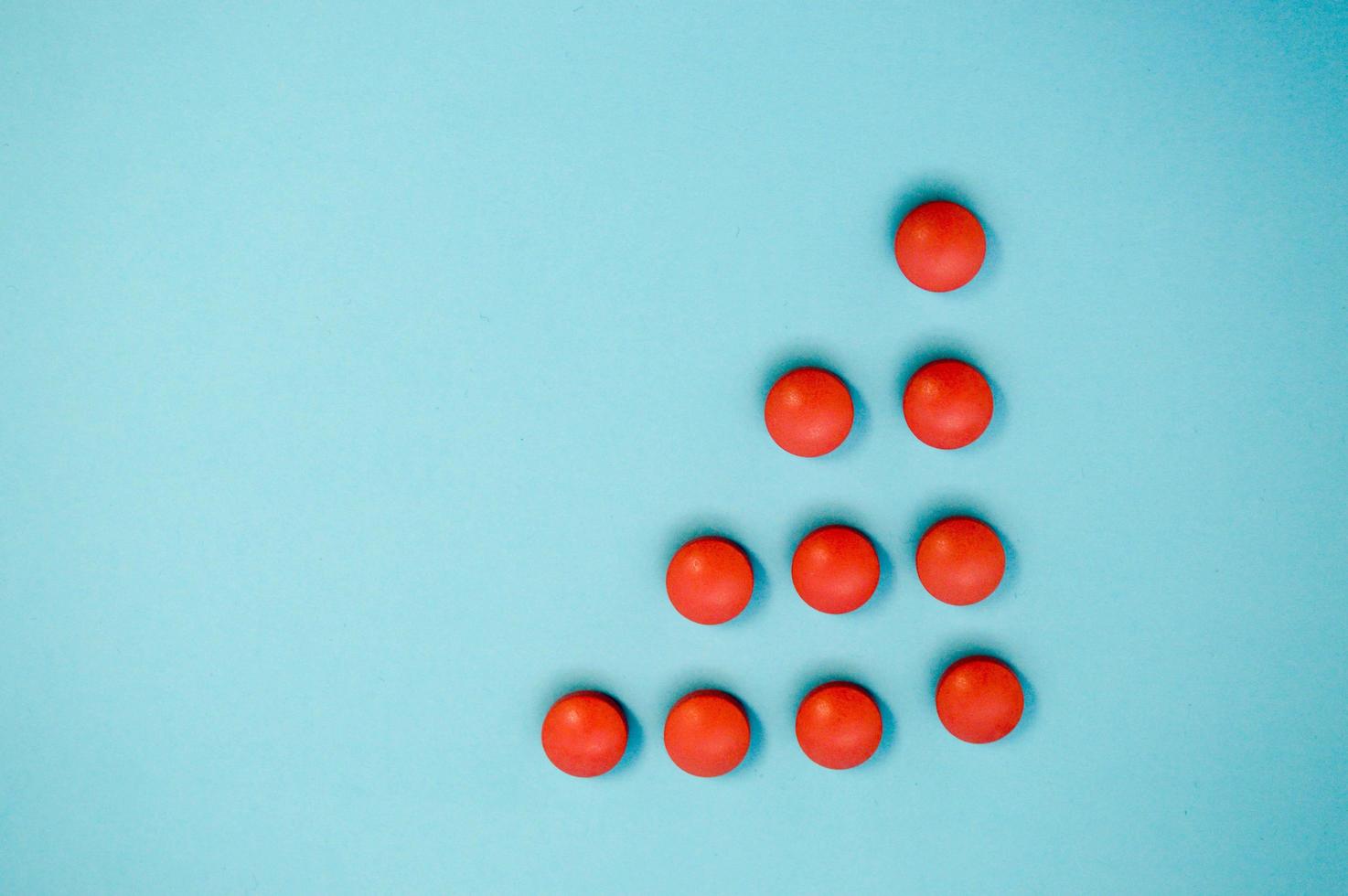 Red round medical pharmaceutical drug pills lie in the shape of a triangle or arrow on a blue background photo