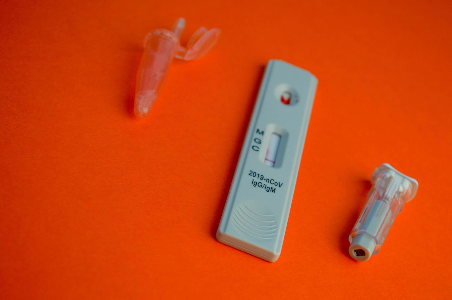 test for coronavirus on an orange background. on a matte background a sensitive strip for coronavirus, a lancet. next to the container for the physical solution. home test kit for coronavirus photo