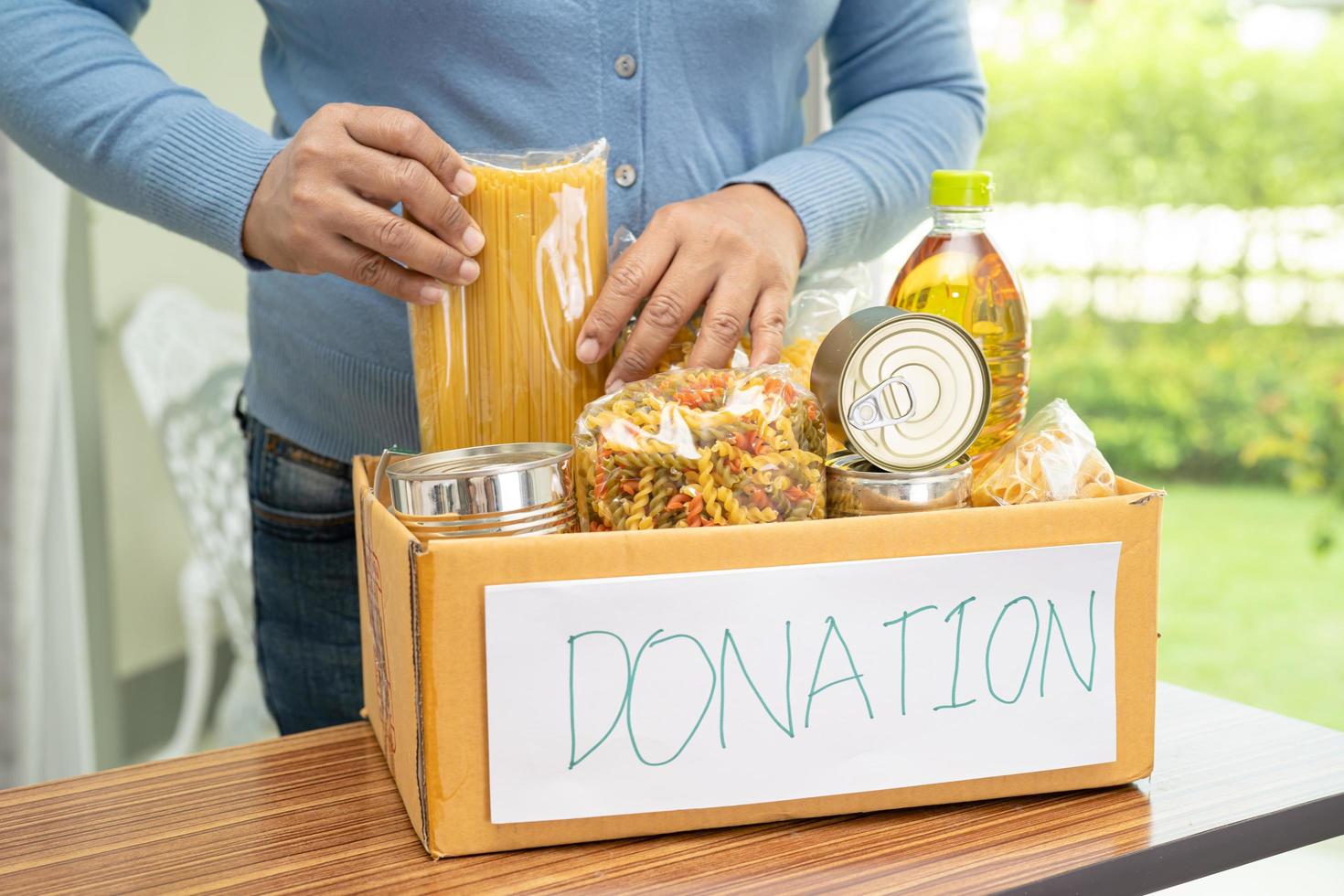 Volunteers putting various dry food in donation box for help people. photo