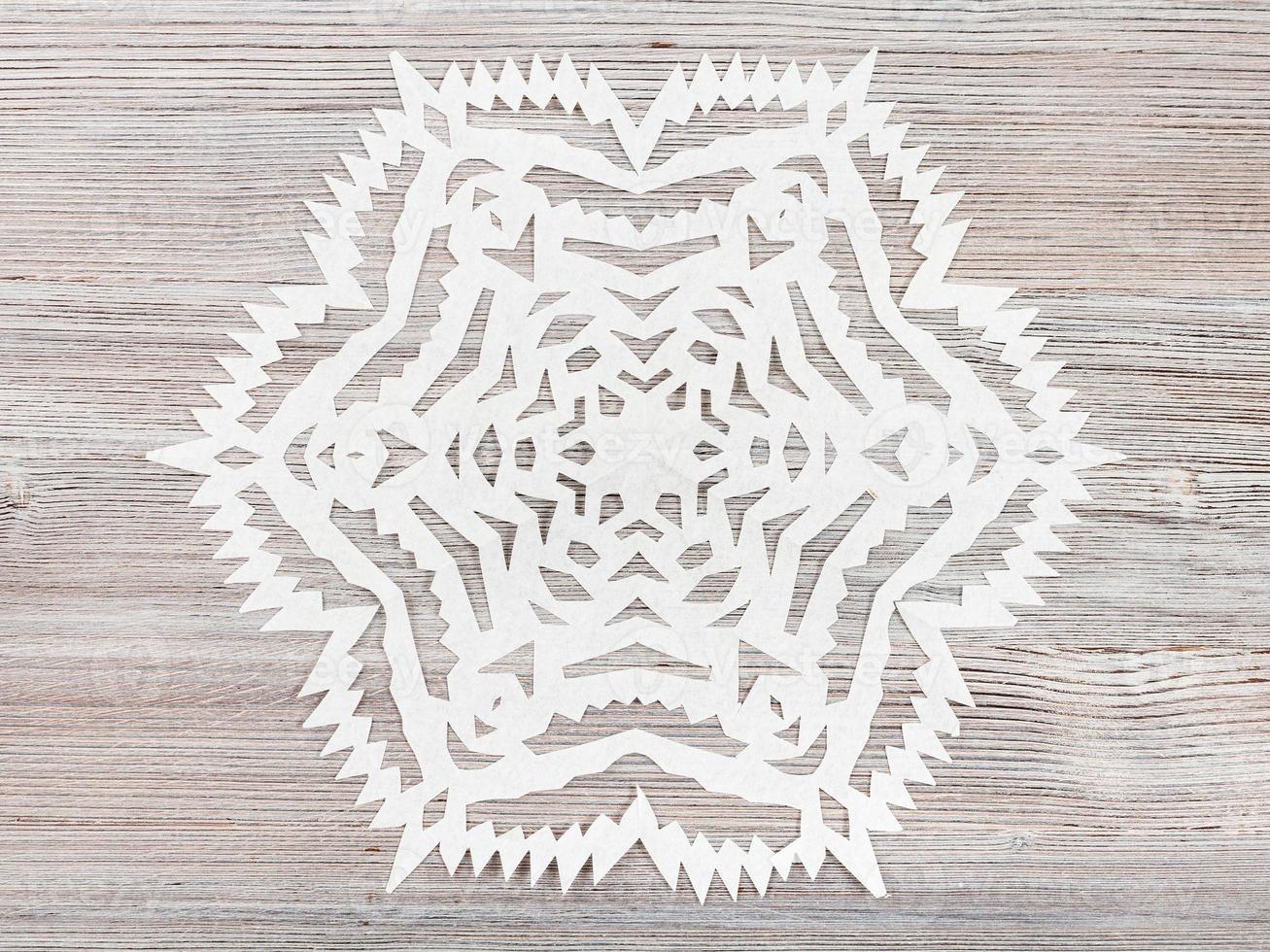 snowflake carved from paper on light brown table photo