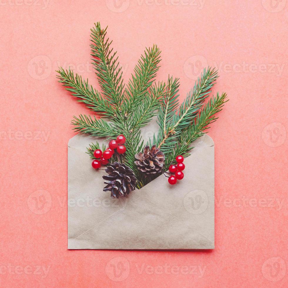 decoración navideña en sobre, conos de ramita de abeto sobre fondo de papel rojo foto
