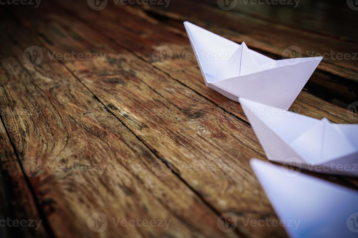 Origami, white paper boat isolated on a wooden floor. Paper boats mean walking. feeling of freedom leadership photo