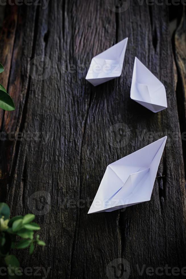 Origami, white paper boat isolated on a wooden floor. Paper boats mean walking. feeling of freedom leadership photo