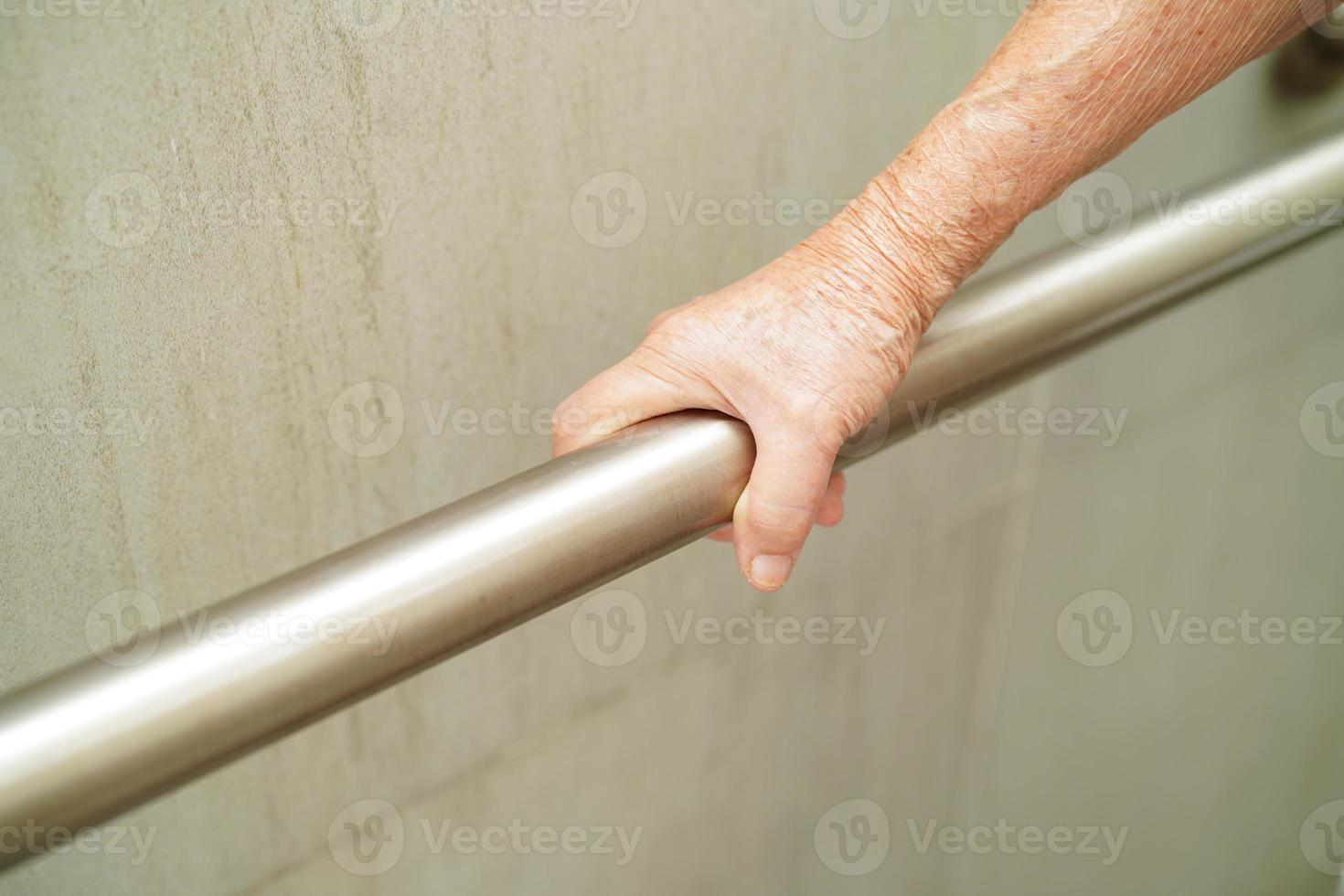 Asian elderly old woman patient use toilet support rail in bathroom, handrail safety grab bar, security in nursing hospital. photo