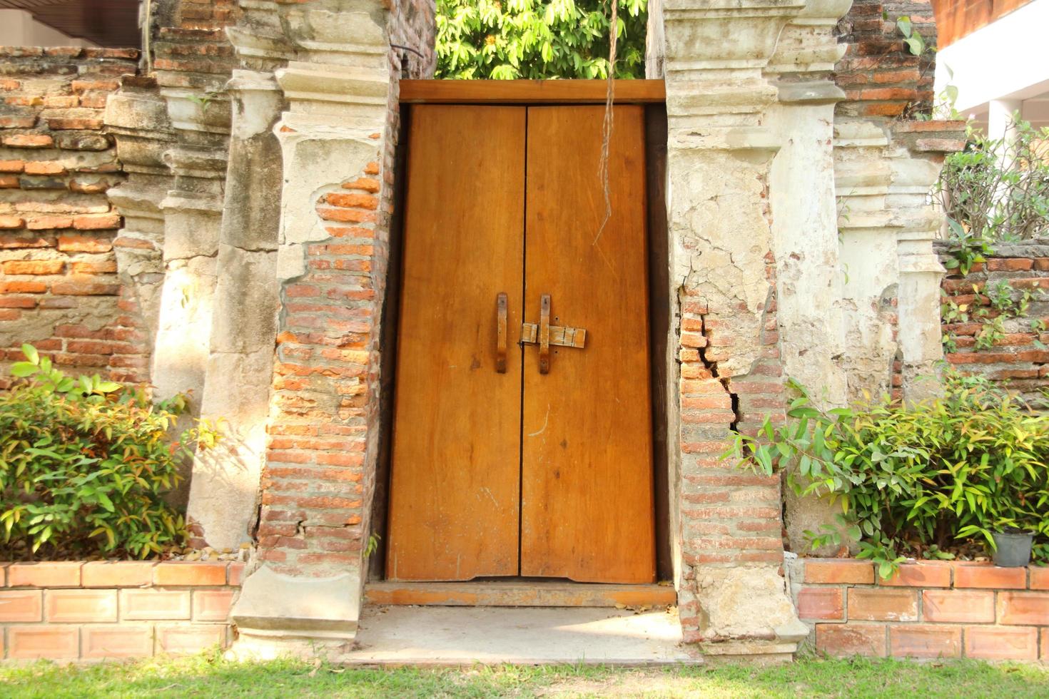 Painted light brown wood door between broken bricks wall.The door closed but unlock. photo