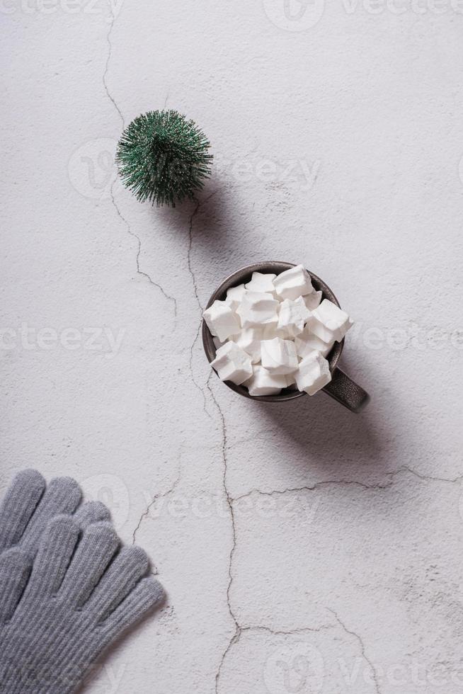 Drink with marshmallow, christmas tree and knitted gloves on plaster. Top and vertical view. photo