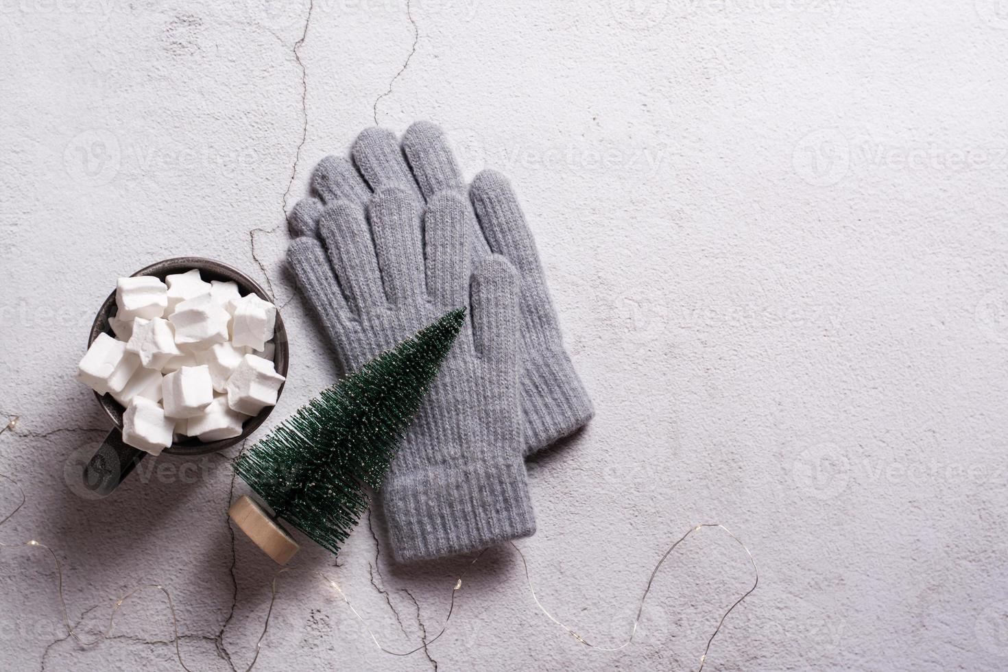 cacao con malvaviscos, guantes de lana y un árbol de navidad en yeso. vista superior. foto