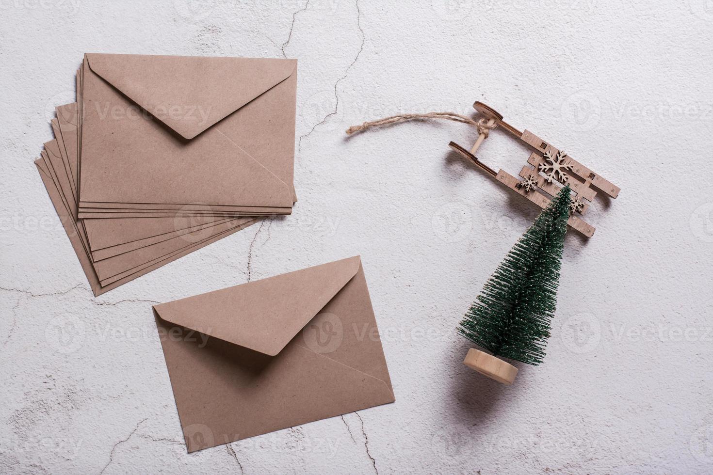 Empty craft envelopes, a Christmas tree and a wooden sledge on plaster. Top view. photo