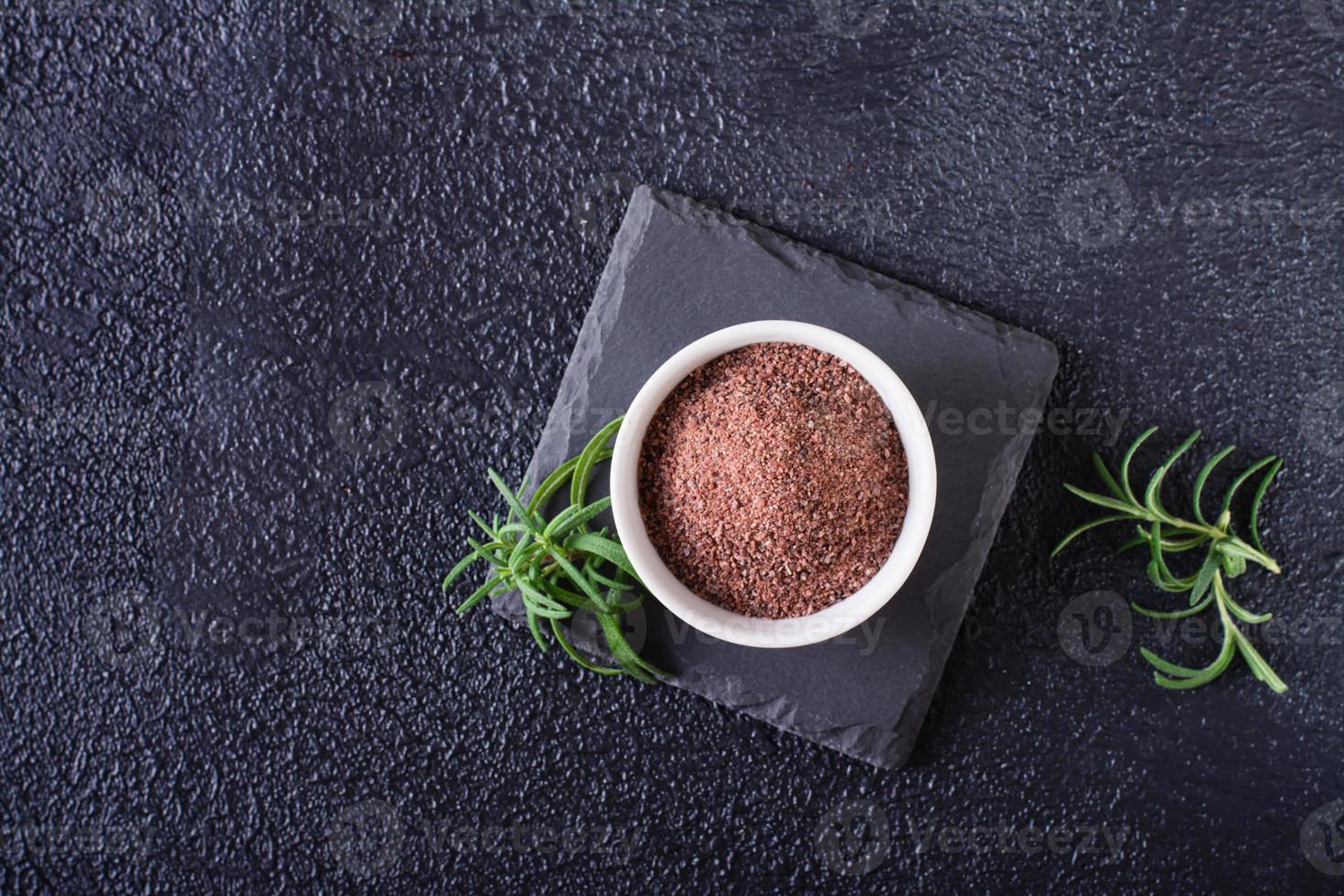 Black Himalayan kala namak salt in a bowl and rosemary on a black background. Top view. photo