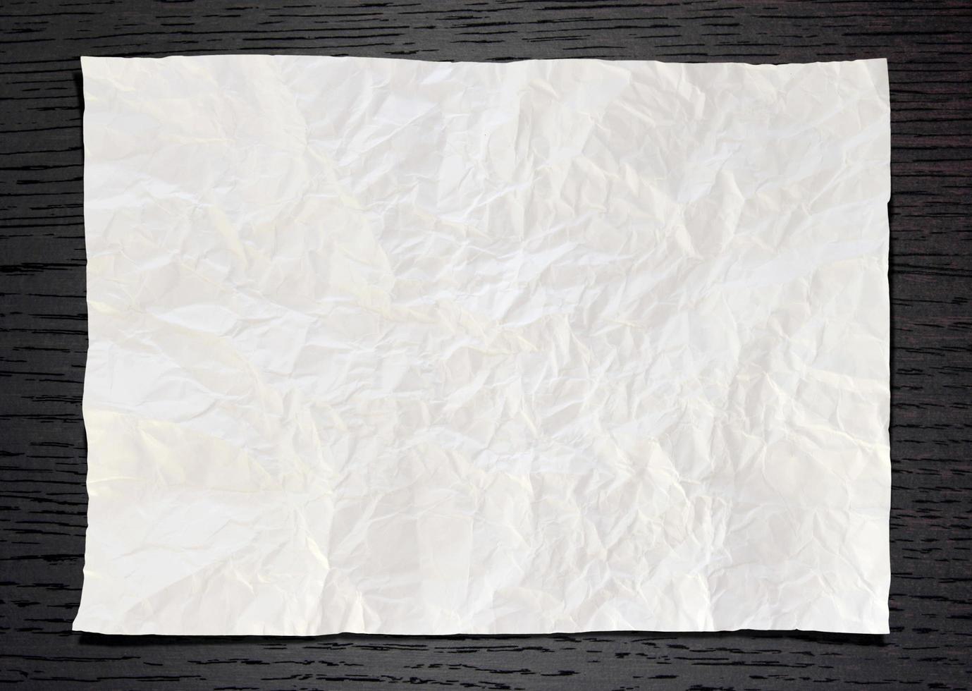 Wrinkled White paper on dark wood background photo