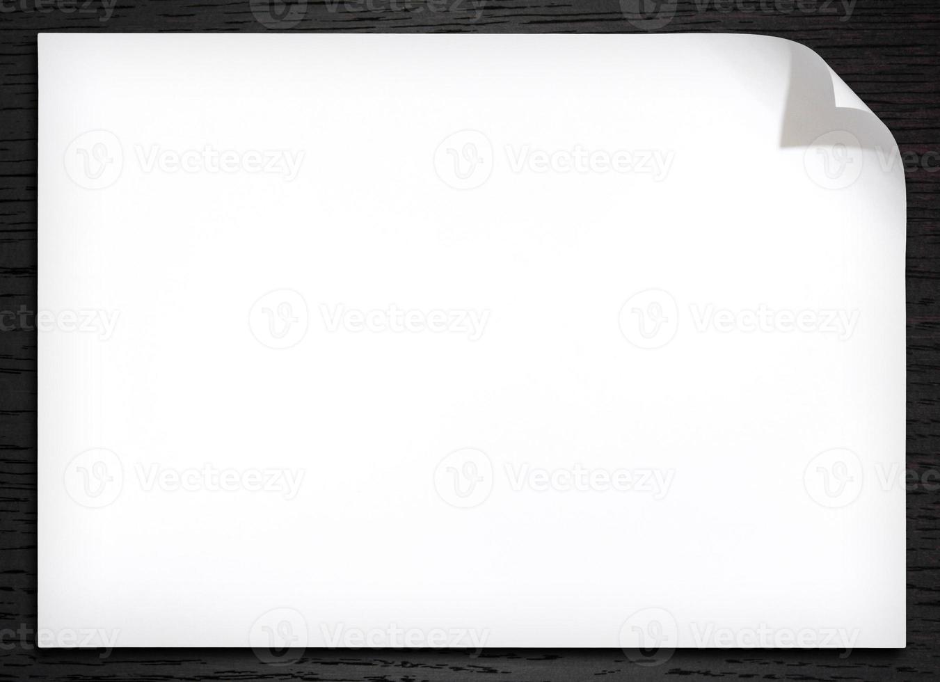 Blank white paper with corner curl on the dark wood background photo